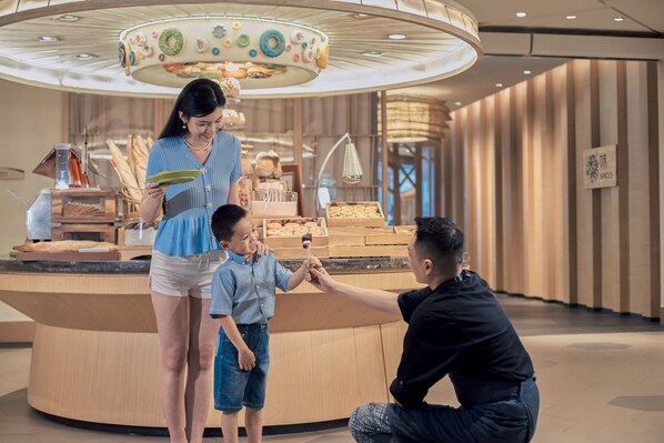 A modern interior with a central counter displaying pastries and a decorative ceiling.