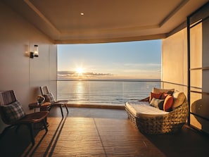 A balcony with a view of the sea at sunset, wooden flooring, and seating arrangements. - Crowne Plaza Sanya Haitang Bay Resort by IHG (Sanya)