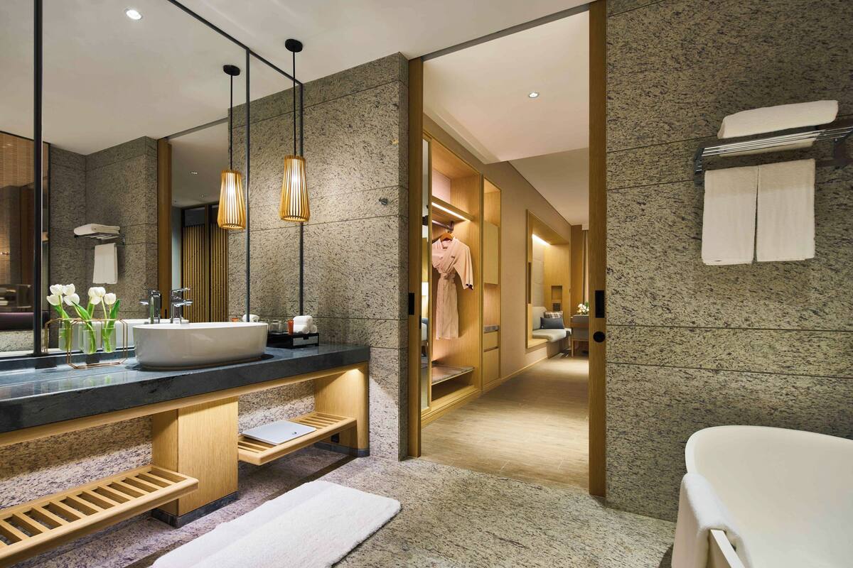 Ein modernes Badezimmer mit einem großen Waschbecken, einem Holz-Waschtisch und einer bodenebenen Dusche.