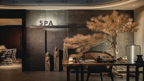 A modern spa area with a reception desk, seating, and a decorative tree.