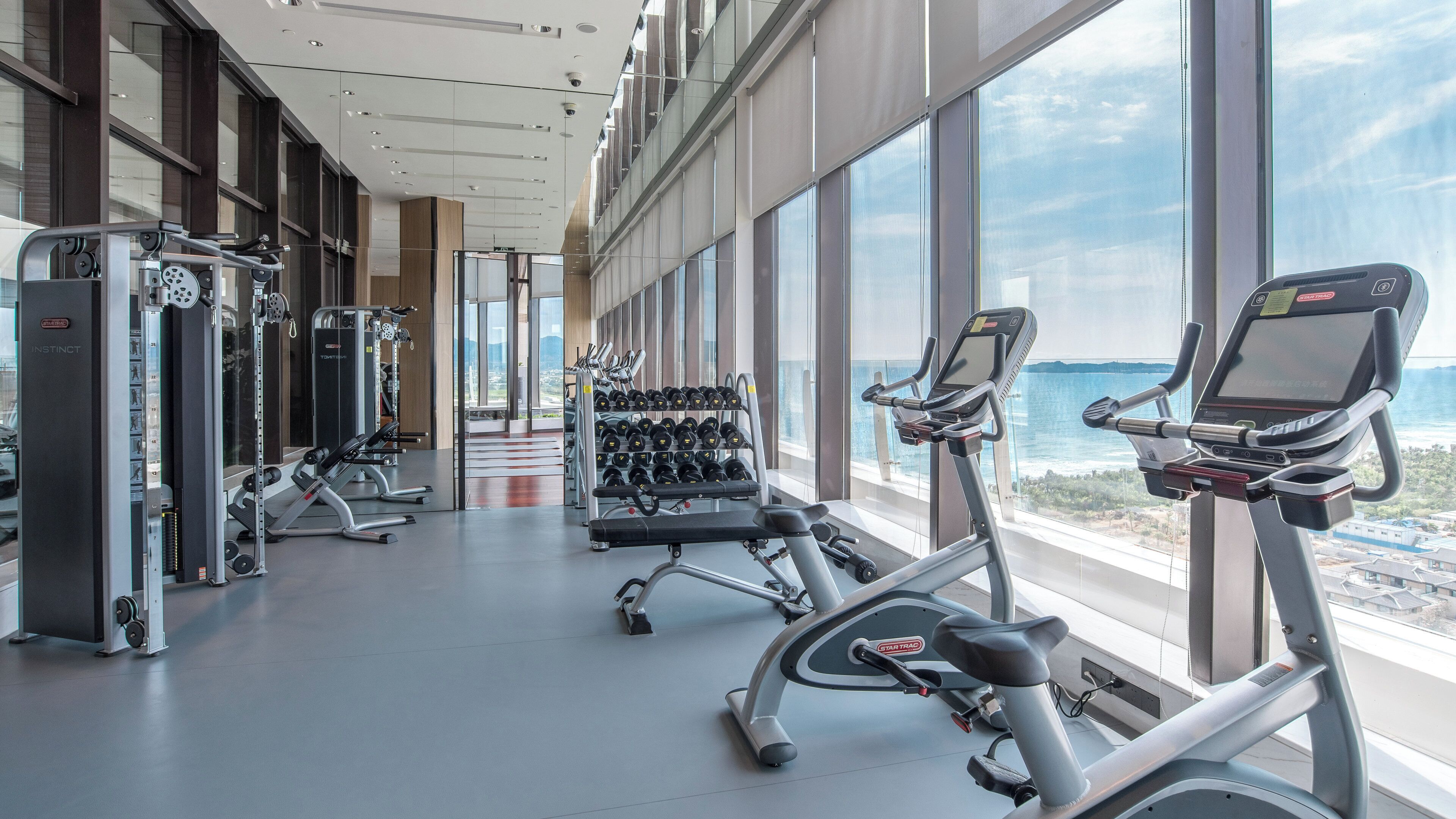 A gym with cardio machines, weightlifting equipment, and dumbbells.