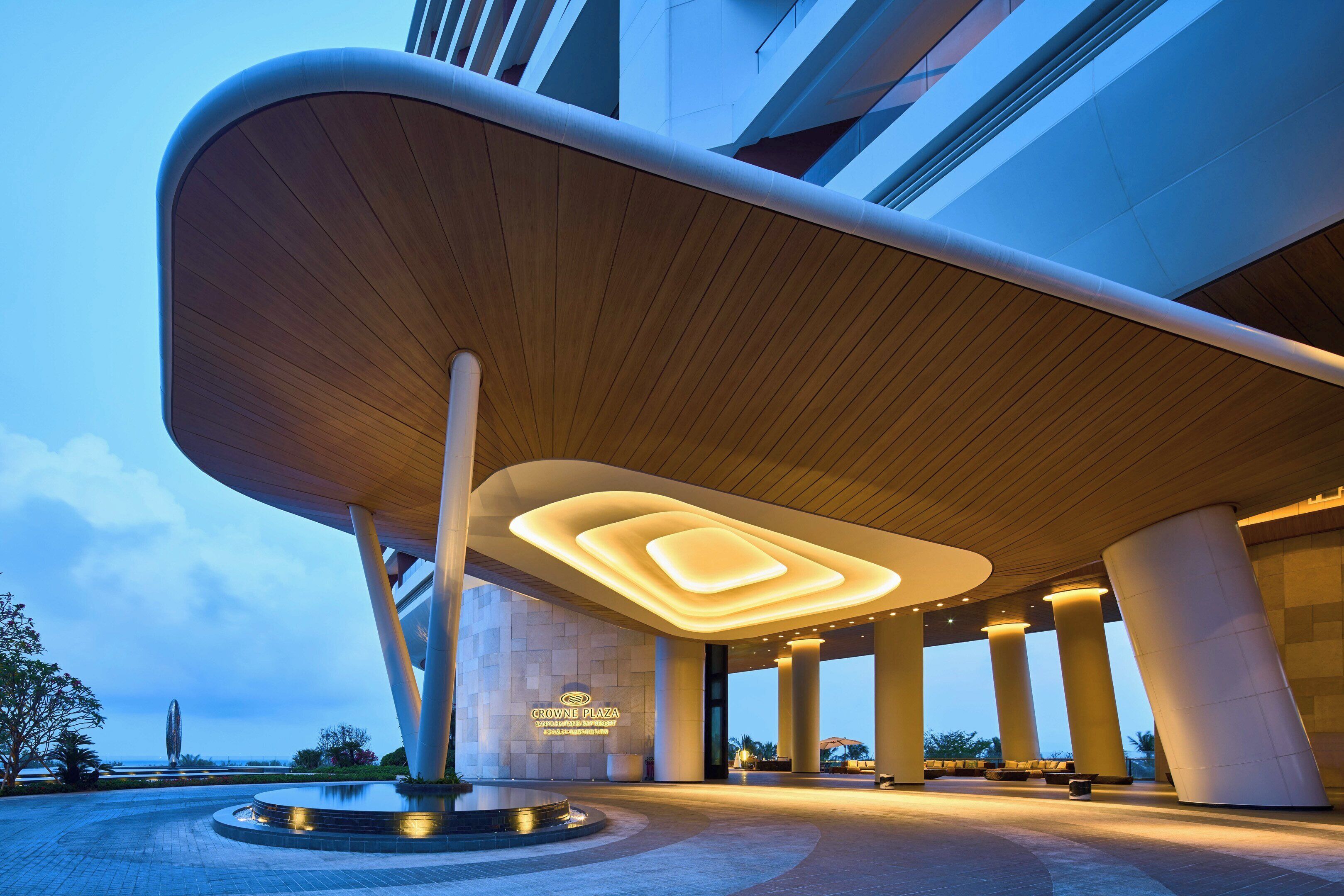 A modern building with a unique curved roof structure and illuminated understructure, likely a hotel or resort.