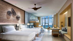 A hotel room with two beds, a sofa, a desk, and a large window with a view.