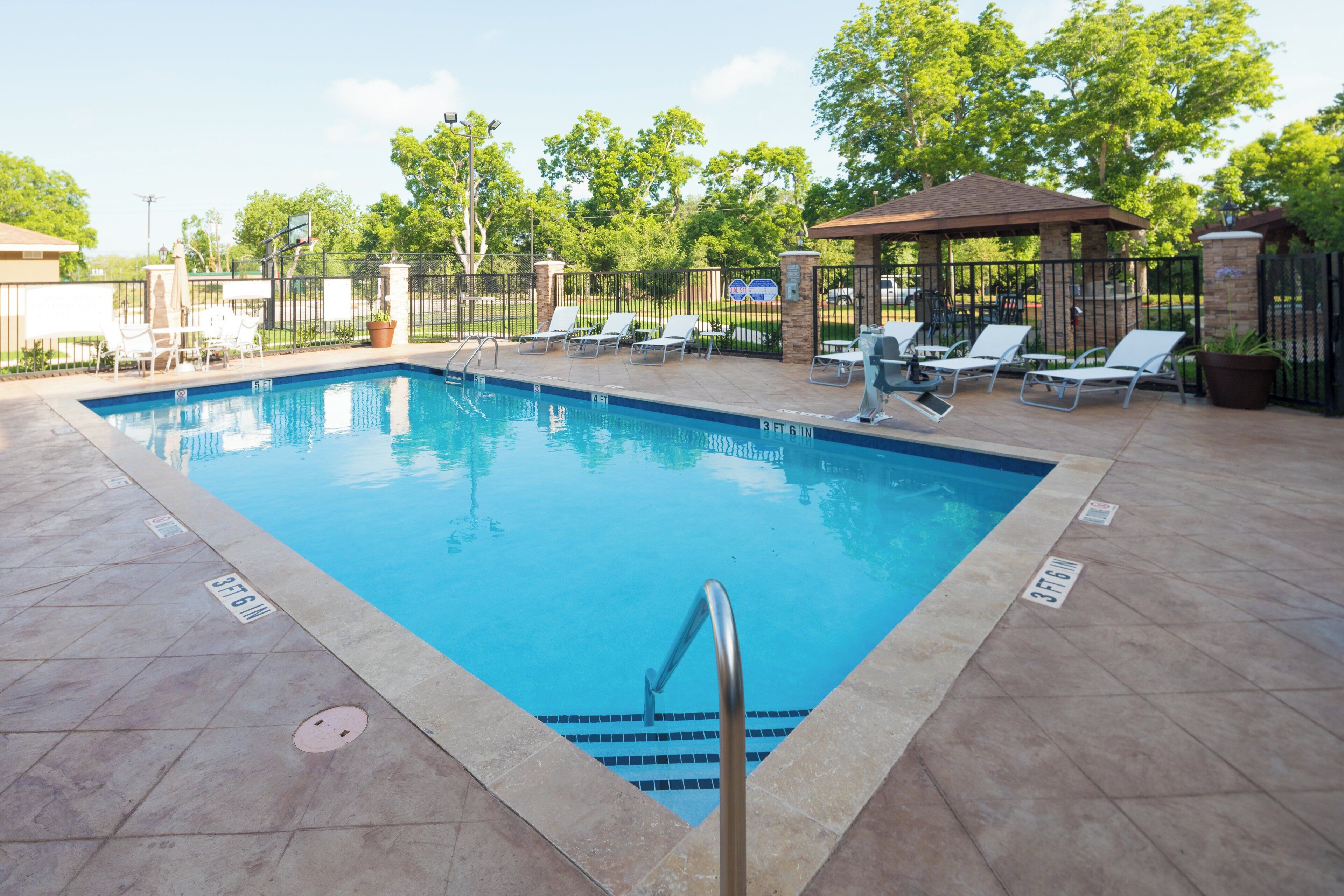 Una piscina al aire libre, sillones reclinables de piscina