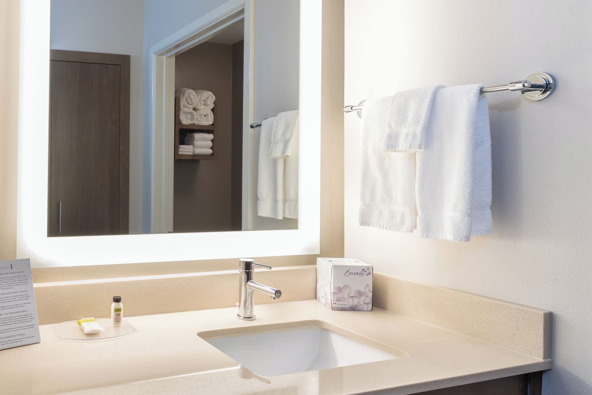A modern bathroom with a large mirror, a sink, and a towel rack.
