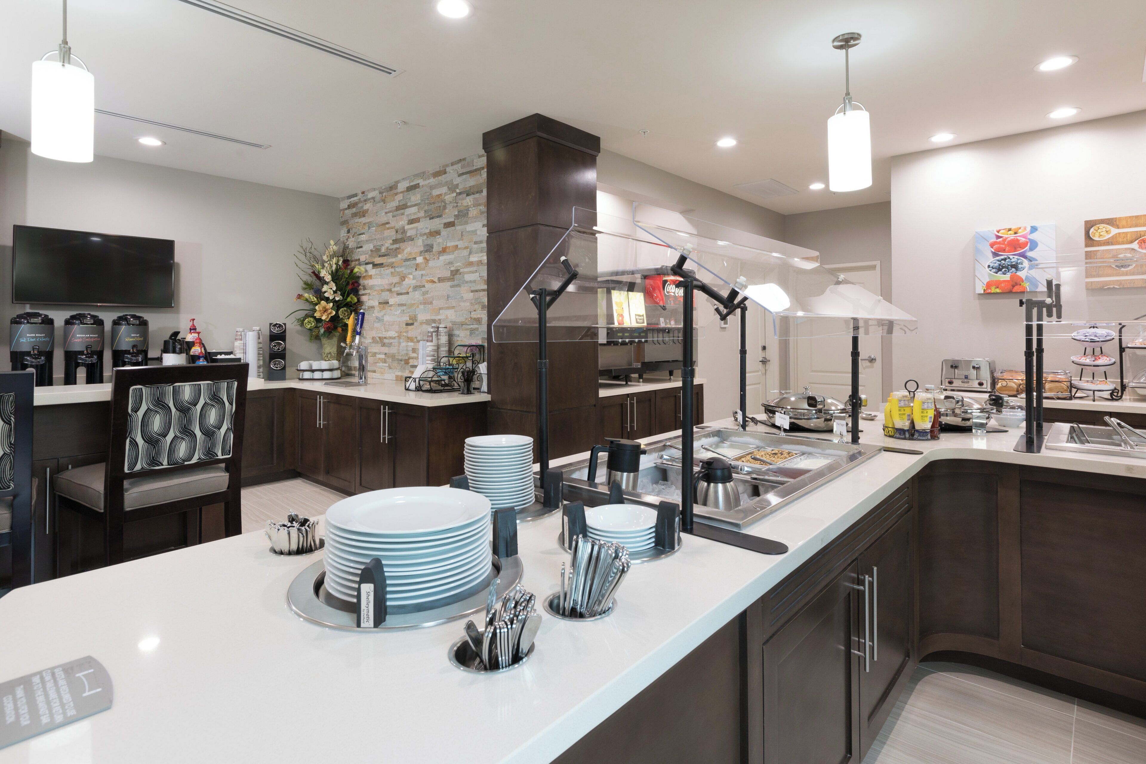 Una cocina moderna con una isla central, un televisor de pantalla plana y una estación para café.
