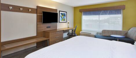 Habitación de hotel con cama, escritorio, silla, televisor y ventana con vistas.