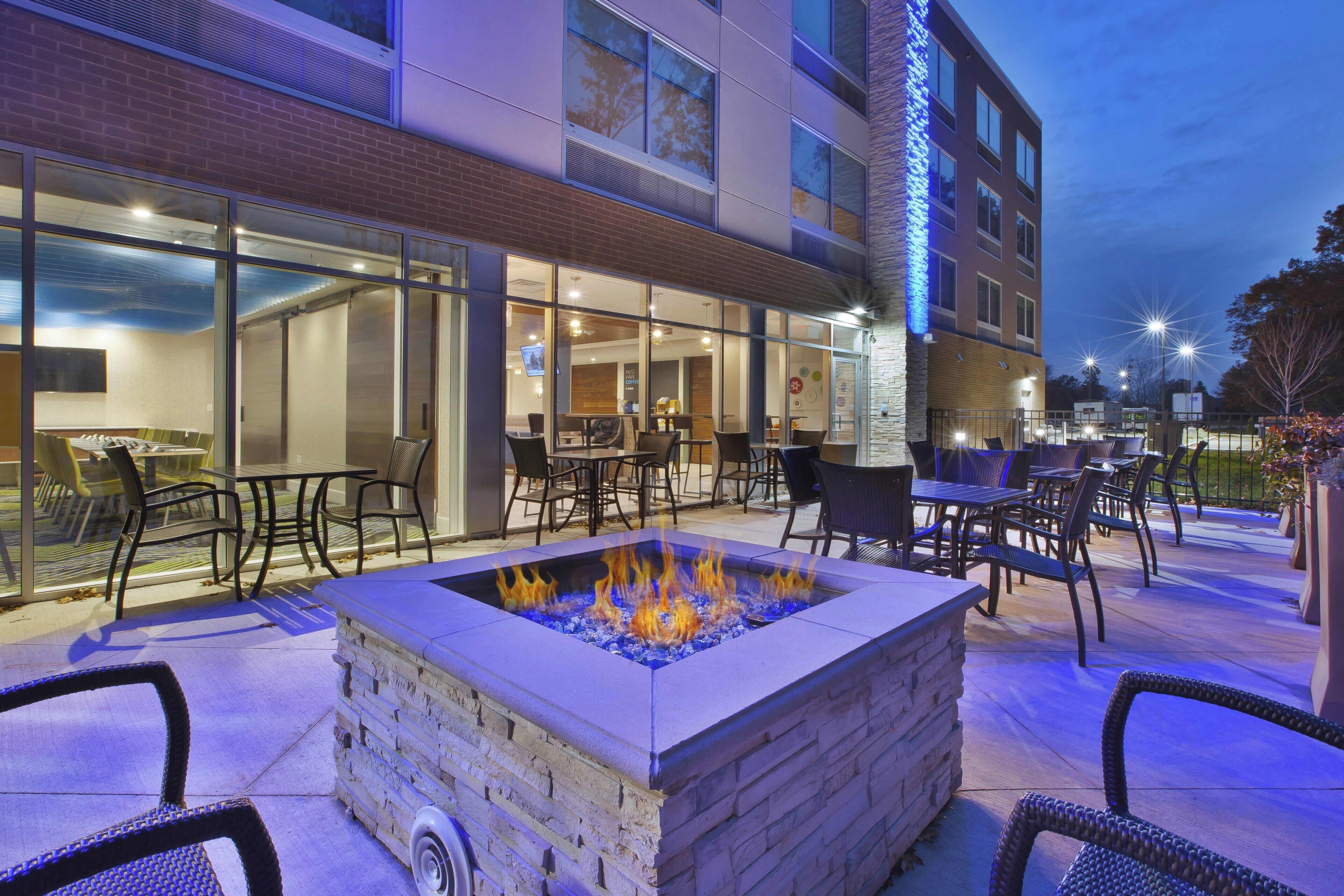 An outdoor seating area with a fire feature, tables, and chairs.