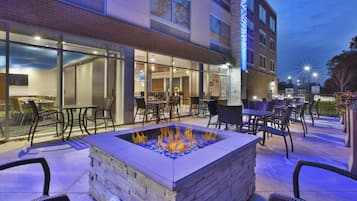 An outdoor seating area with a fire feature, tables, and chairs.