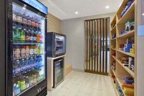 Ein Verkaufsbereich mit verschiedenen Getränken, einem kleinen Kühlschrank und Regalen voller Snacks und anderer Waren.