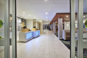 A hotel lobby with a reception desk, a market sign, and a seating area with a patterned rug.