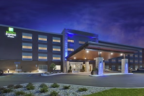 Un edificio de Holiday Inn Express & Suites con un diseño moderno, que presenta una entrada cubierta y fachada de piedra.
