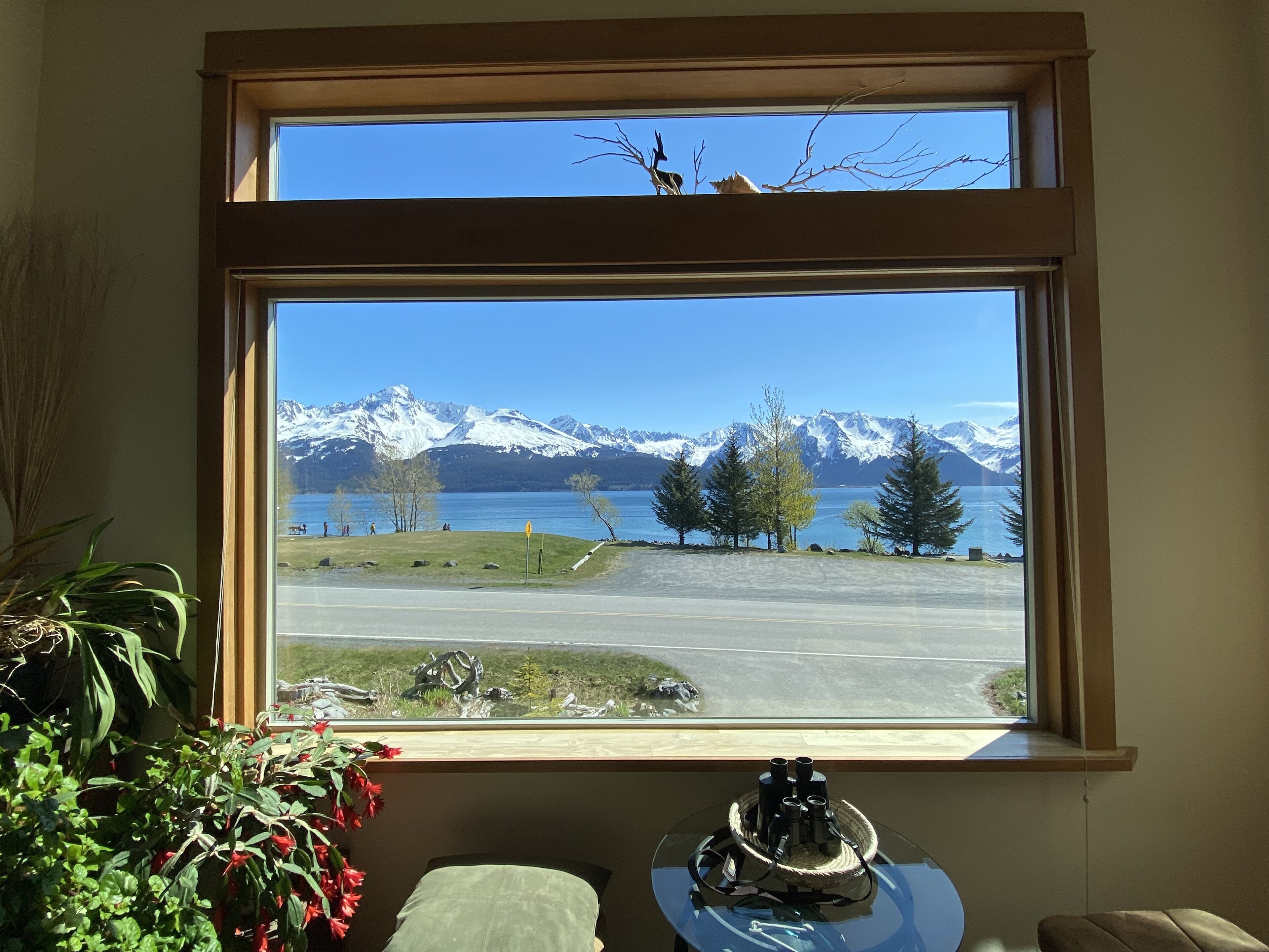 A room with a large window overlooking a lake and mountains.