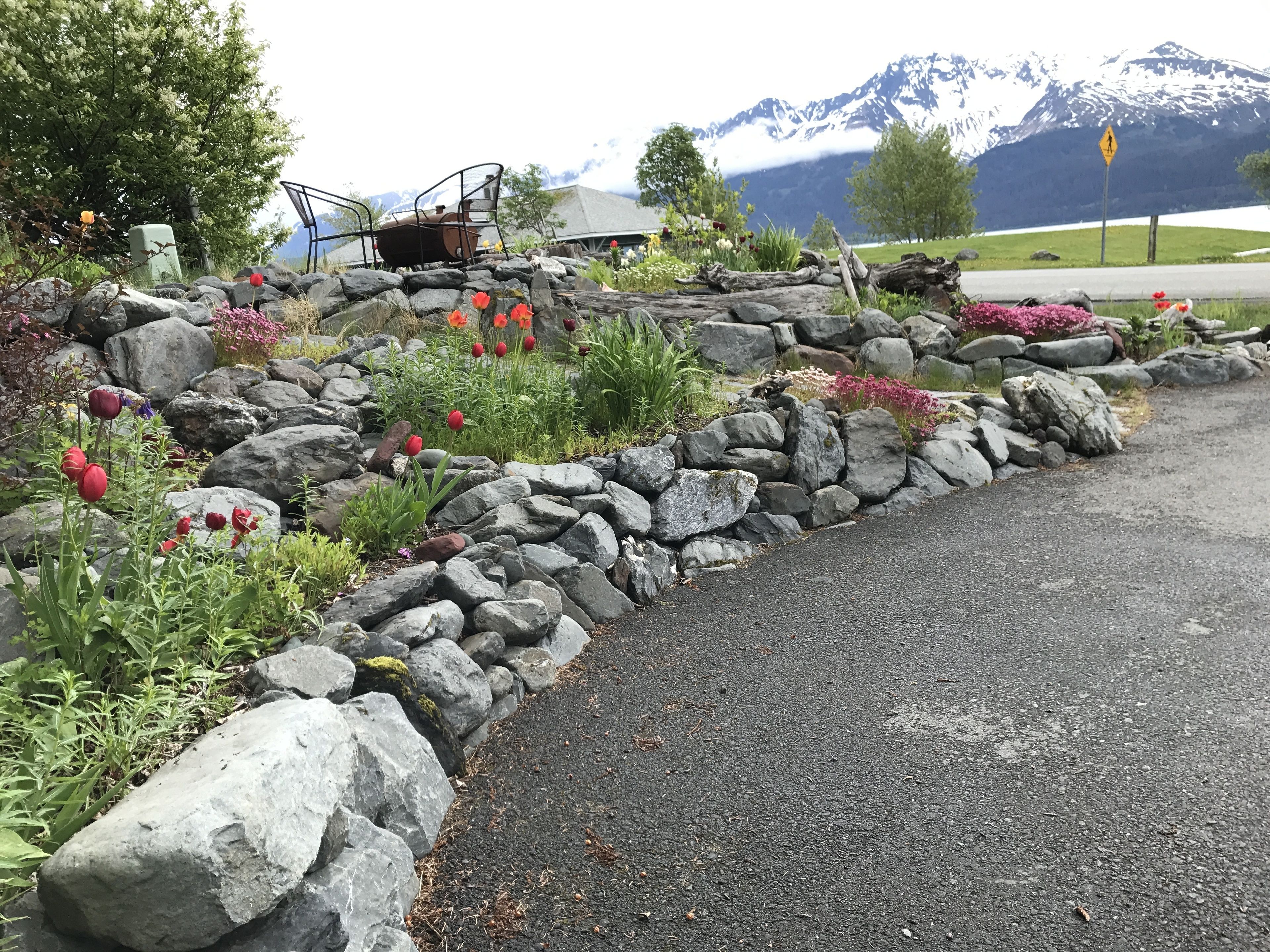 A stone wall with a flower bed and a chair.