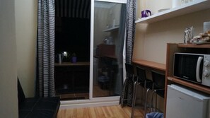 Una cocina compacta con microondas, refrigerador y una pequeña zona de comedor con sillas.