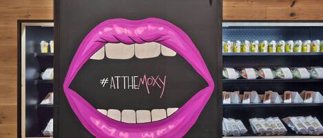 Una pared con una ilustración grande de labios rosados y el hashtag #ATTHEMOXY.