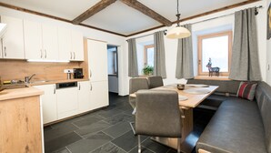 A modern kitchen with white cabinets, a wooden countertop, and a dining area with a wooden table and chairs.