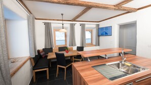 A compact kitchen with a wooden countertop, a built-in sink, and a dining area with a table and chairs.