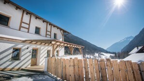 A white building with wooden beams, a wooden fence, and a mountain backdrop.