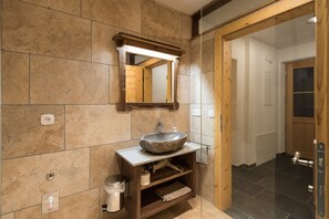 A bathroom with a stone sink, wooden vanity, and a mirror. - Gletscher Appartements (Flattach)