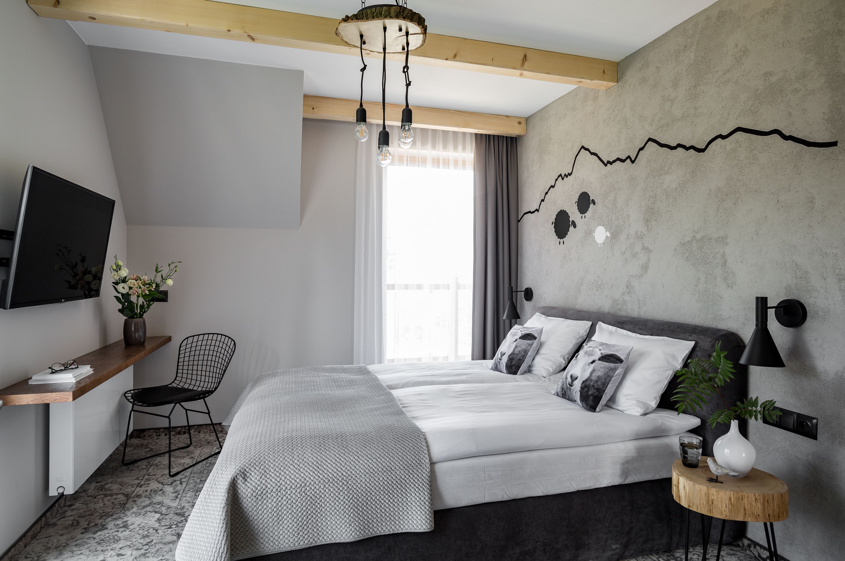 Un dormitorio moderno con cama, escritorio, silla, televisor y una obra de arte en la pared.
