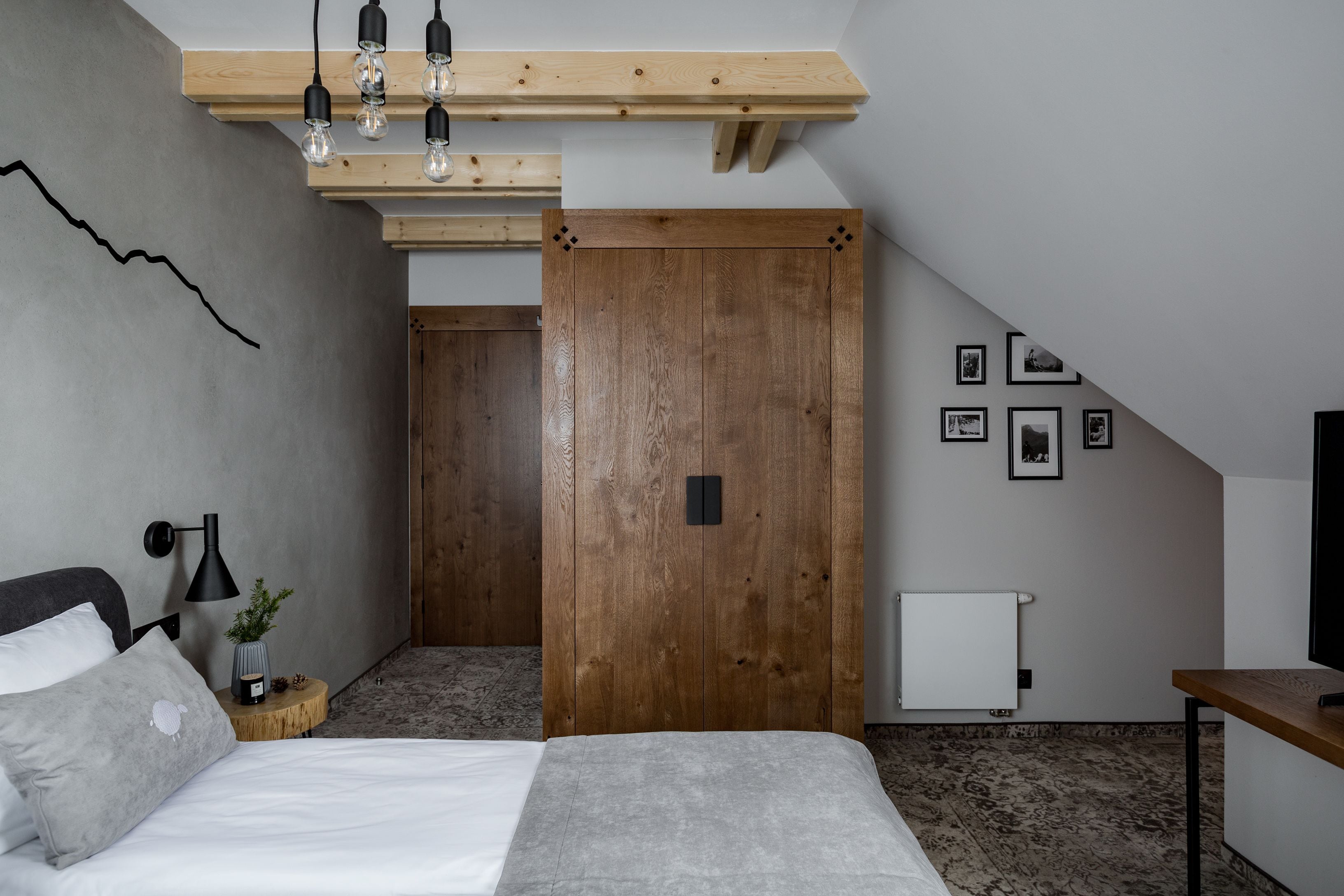 Un dormitorio con una cama, mesita de noche, lámpara y un armario de madera.