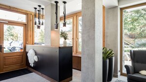 Et moderne interiør med en træreception, sorte hængende lamper, store vinduer og udsigt udad.