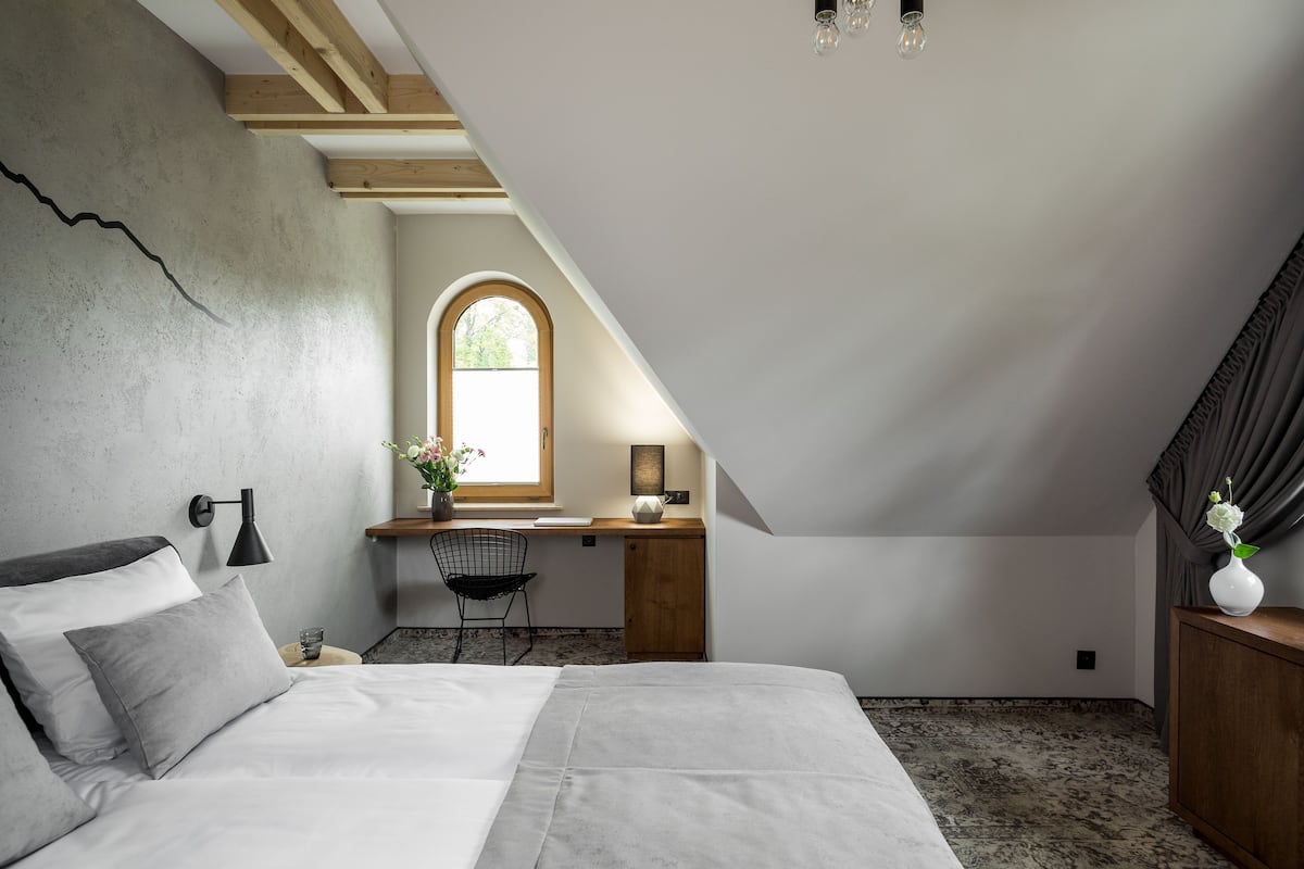 A bedroom with a bed, a desk, and a window.