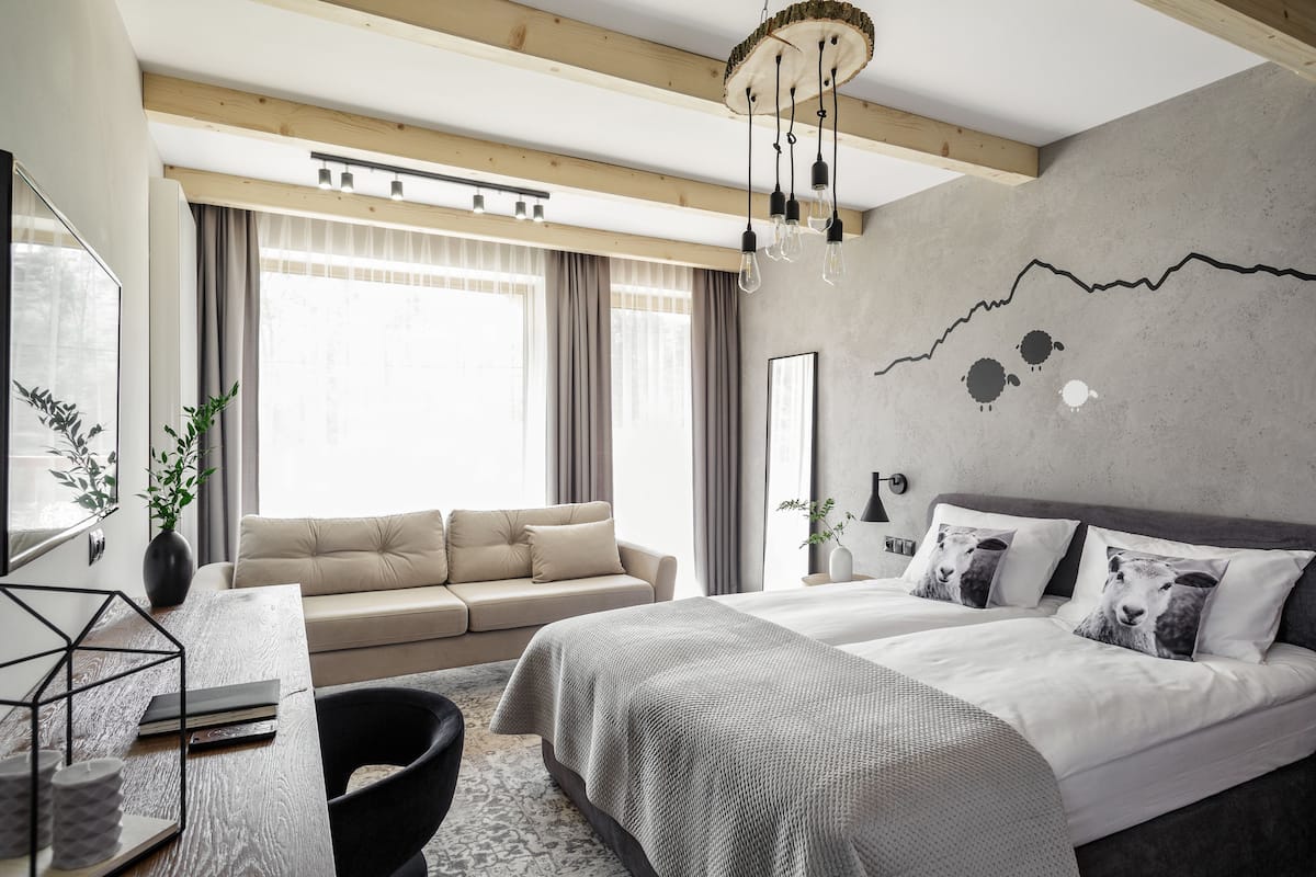 A modern bedroom with a large bed, a sofa, and a desk.