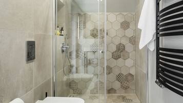 Un baño moderno con ducha de vidrio, inodoro y barra para toallas.
