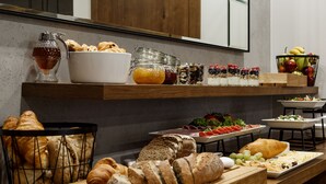 En morgenmadsbuffet med et udvalg af mad og en skål med frugt.