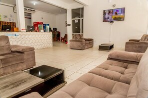 Een ruime woonkamer met een zithoek, een salontafel en een flatscreen televisie aan de muur.