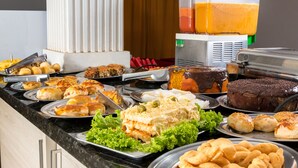Ein reichhaltiges Buffet mit verschiedenen Speisen, darunter Kuchen, Gebäck und einem Saftspender.