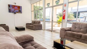 Eine Hotelhalle mit Sofas, einem Flachbildfernseher und einer Glastür zum Außenbereich.