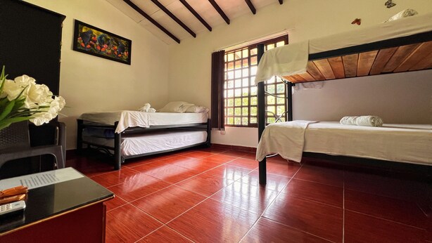 A room with two beds, a desk, and a window. - Paraiso Cocora (Salento)
