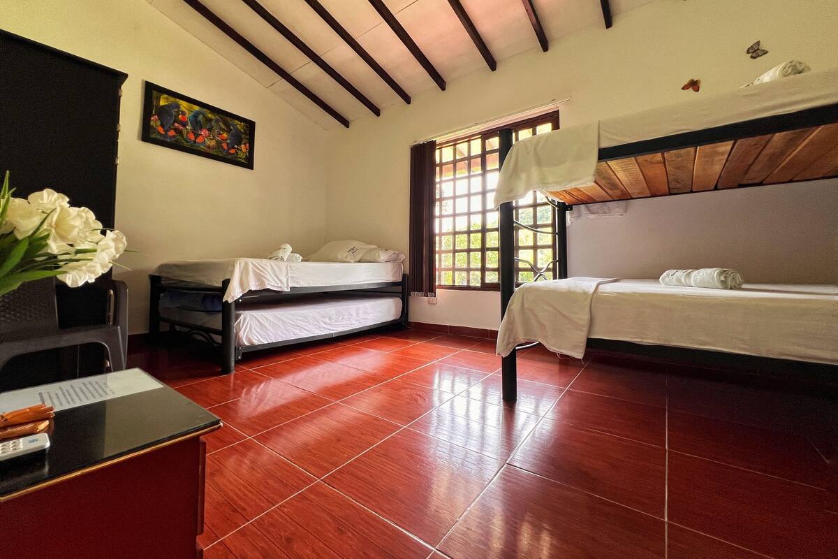 Una habitación con dos camas, un escritorio y una ventana.