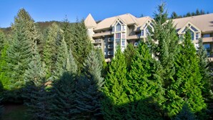 Un hôtel à plusieurs étages, doté d’une architecture moderne, entouré d’une forêt dense de conifères.