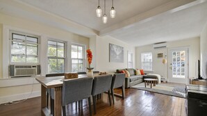 A spacious living room with a dining area, large windows, and a modern kitchen in the background. - Top-Floor Princeton Condo w/private balcony (Princeton)