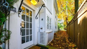 A narrow pathway leading to a white house with a 'WO' sign, a wooden fence, and autumn leaves on the ground. - Top-Floor Princeton Condo w/private balcony (Princeton)