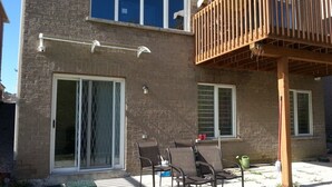A two-story house with a balcony, a sliding glass door, and a patio with outdoor furniture. - Walkout Ravine, Cottage feeling basement (Richmond Hill)