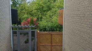 A narrow outdoor pathway with a wooden fence and a small garden area. - Walkout Ravine, Cottage feeling basement (Richmond Hill)