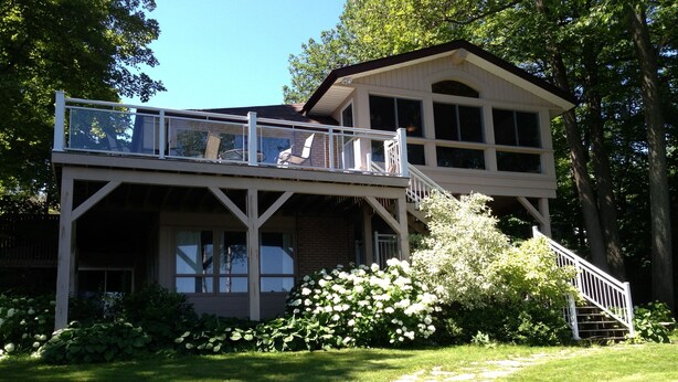 A two-story house with a balcony, a stone pathway, and a garden. - Lake Muskoka in Muskoka Bay (Gravenhurst)