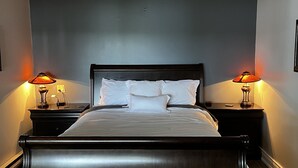 A bedroom with a dark wood bed, two bedside lamps, and a bench. - Lake Muskoka in Muskoka Bay (Gravenhurst)