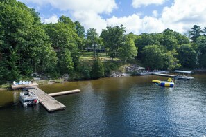 A lake with a dock, a floating platform, and a house in the background.