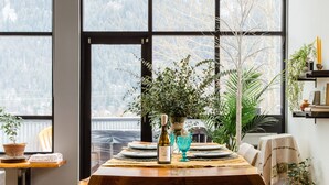 A dining area with a wooden table, benches, and a hanging light fixture. - Lamplighter Grand Loft - contemporary open design & walk anywhere! (Nelson)