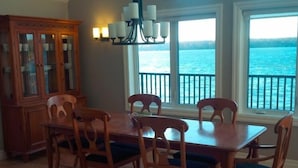 Ein Essbereich mit Holztisch und Stühlen, einer Chandelüster und großen Fenstern mit Meerblick.