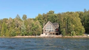 Ein Haus am See mit einem großen Fenster, umgeben von Bäumen.