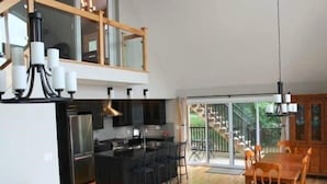 Eine moderne Küche mit einer zentralen Kochinsel, einem Essbereich mit Holzkästen und einer großen Schiebeglas-Zuwegung zu einem Balkon.