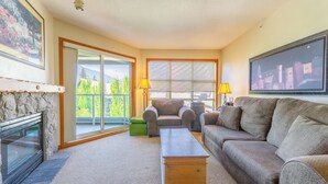 A living room with a fireplace, a sofa, a coffee table, and a large window with blinds.