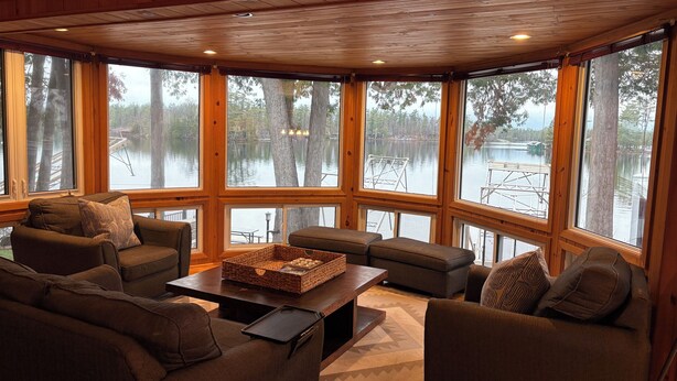 A cozy cabin interior with large windows, a fireplace, and a comfortable seating area. - Family Friendly Stoney Lake Cottage (Lakefield)